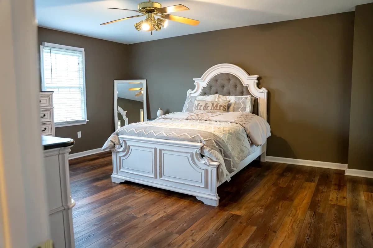 Primary bedroom after the refresh — wood-look flooring and taupe walls