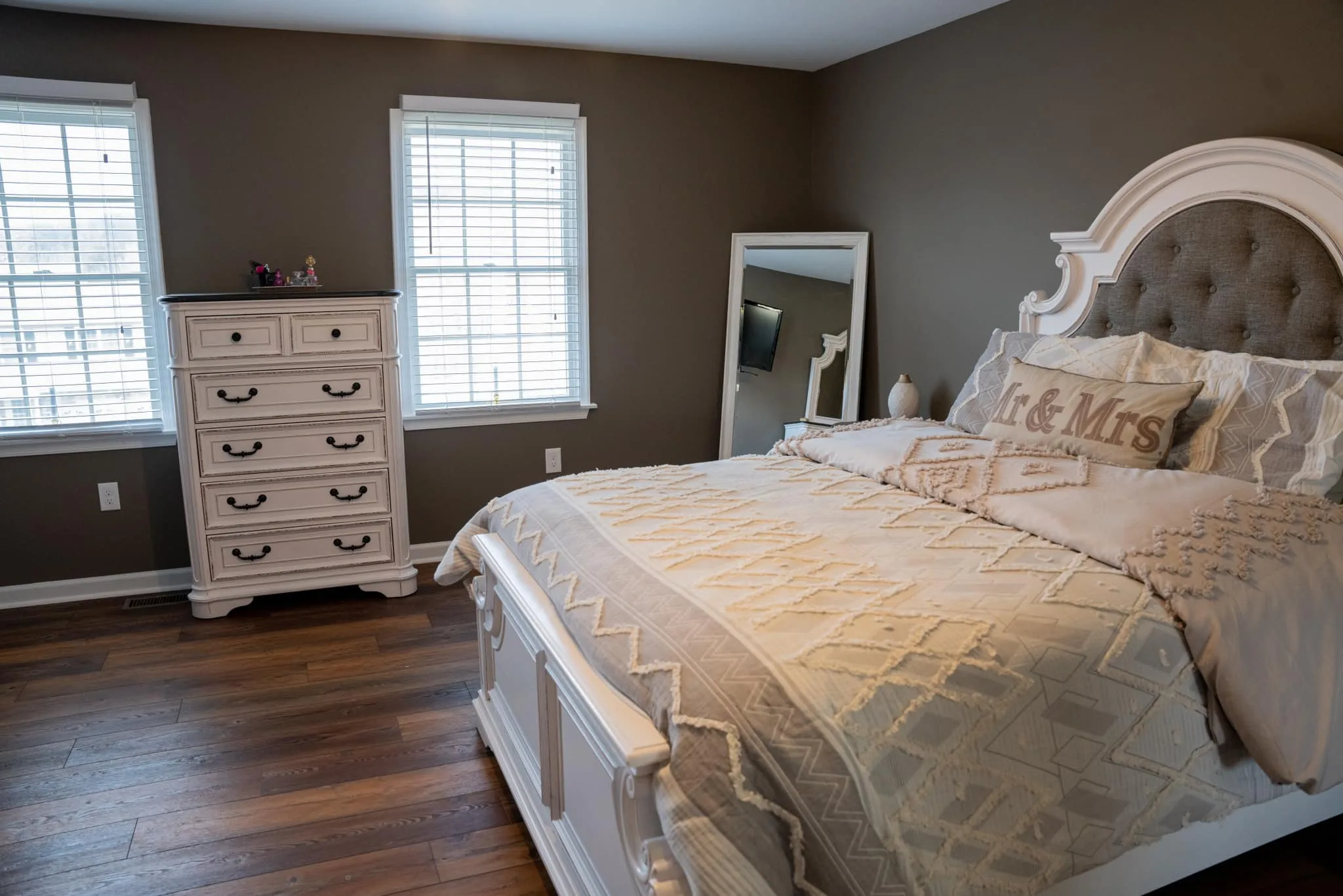 Primary bedroom after the refresh — wood-look flooring and taupe walls