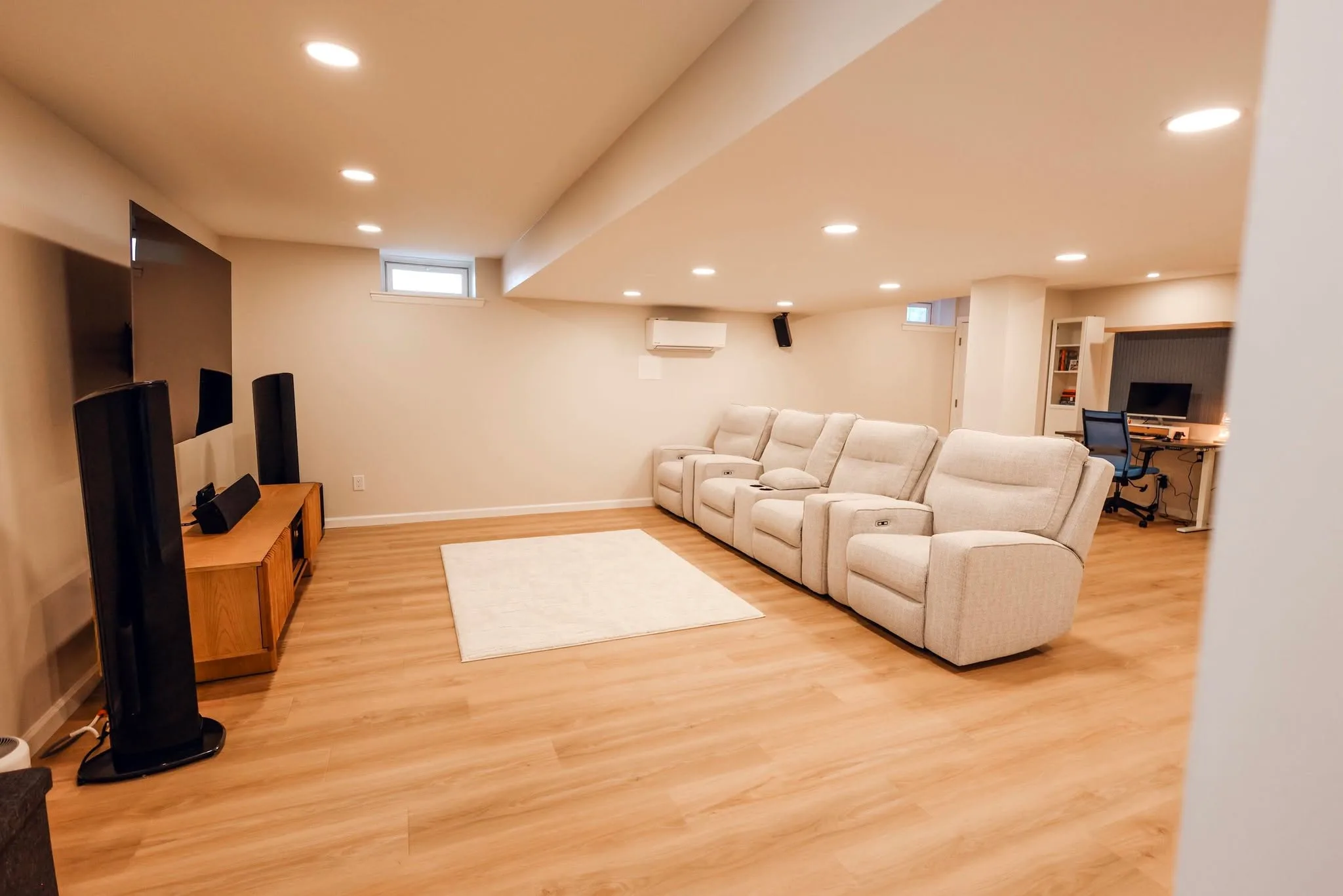 Finished basement media room — LVP flooring, recliner row, wall-mounted TV