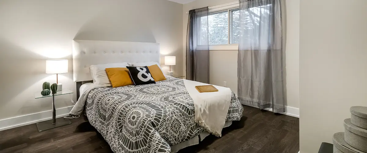 Contemporary bedroom in remodeled basement, with a comfortable bed, stylish decor, and ample natural light.