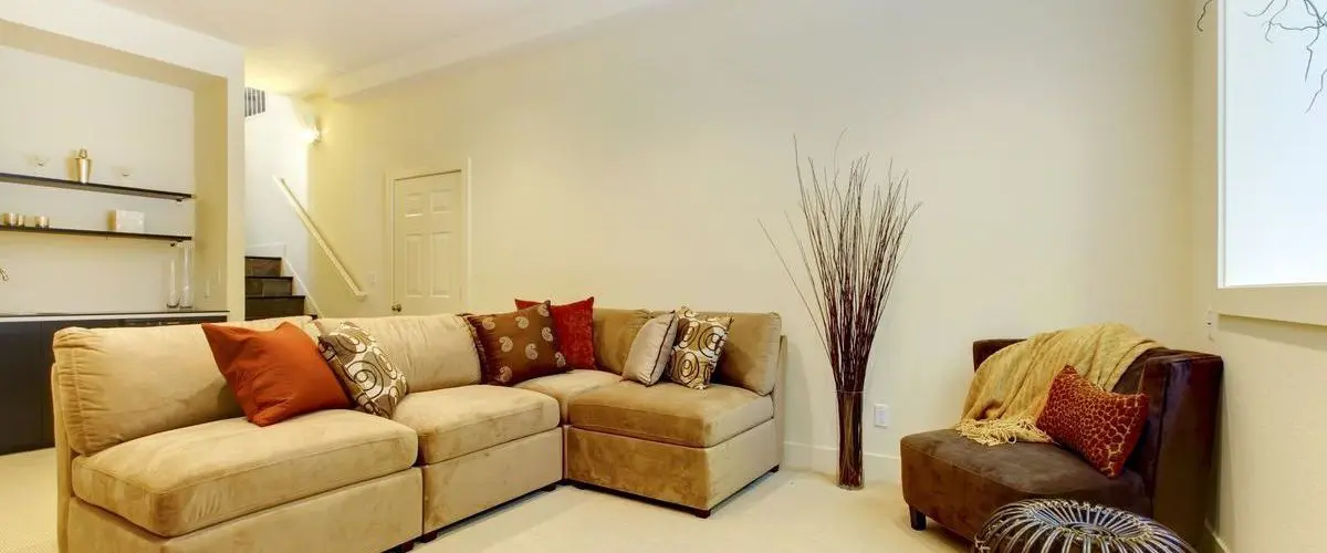 Inviting basement remodeling with a sectional sofa, decorative pillows, and a minimalist aesthetic.