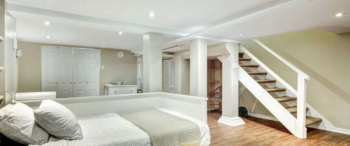 Spacious remodeled basement converted into a guest bedroom with natural light and modern decor.