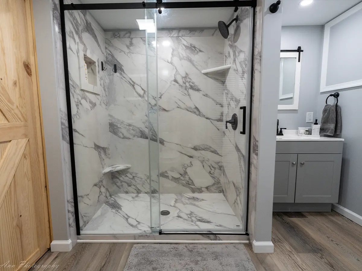 Bathroom with large marble shower, glass doors, and gray vanity