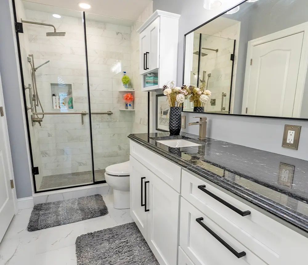 Sleek bathroom with marble shower, white vanity, and black countertop