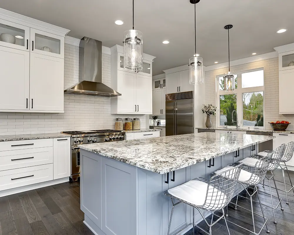 Spacious kitchen with large granite island, white cabinets, and stainless steel range hood