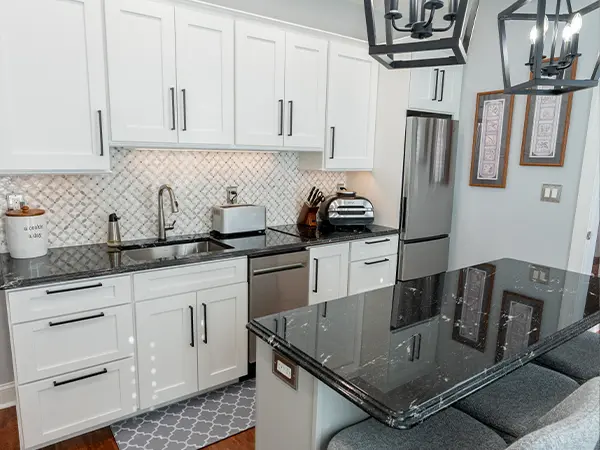 Small kitchen with black granite countertops, white cabinets, and pendant lighting